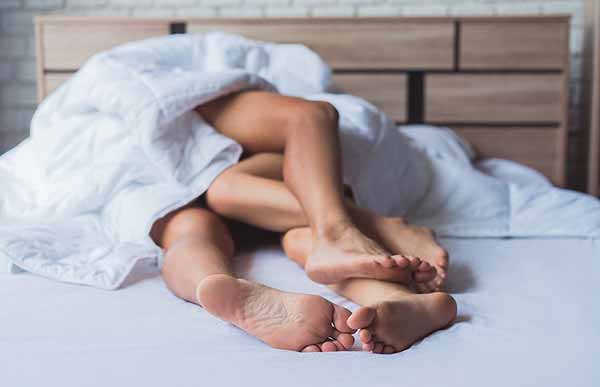 Ноги чоловіка і жінки під ковдрою після сексу